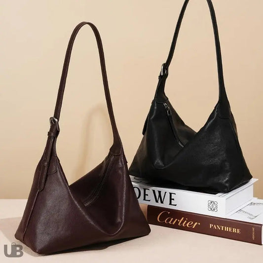 deux sacs fourre tout en cuir véritable l'un marron et l'autre noir , posés sur un support décoratif , et sur deux livre épais
