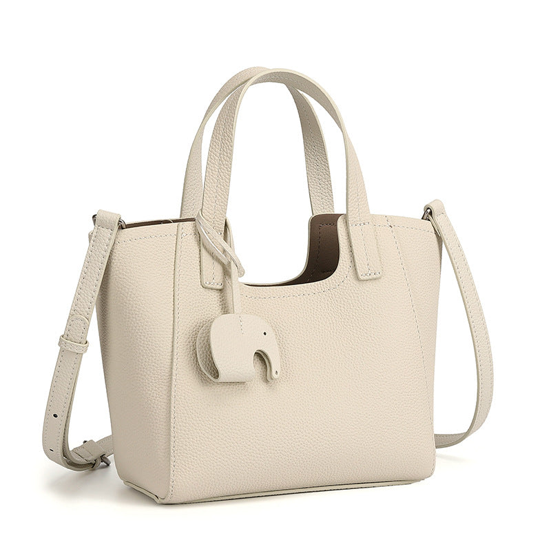 Petit cabas Louise ivoire en cuir grainé, avec charm éléphant et bandoulière