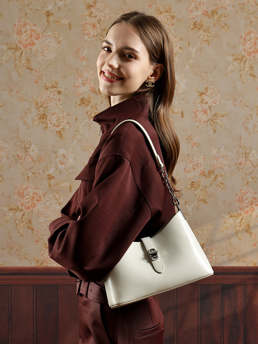 Sac Fanny crème porté à l’épaule avec un manteau bordeaux