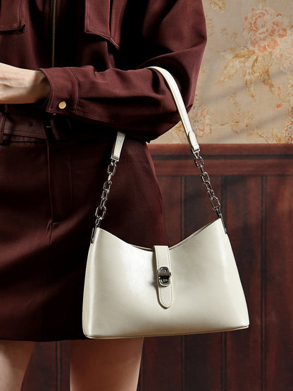 Sac Fanny crème porté au bras avec un manteau bordeaux