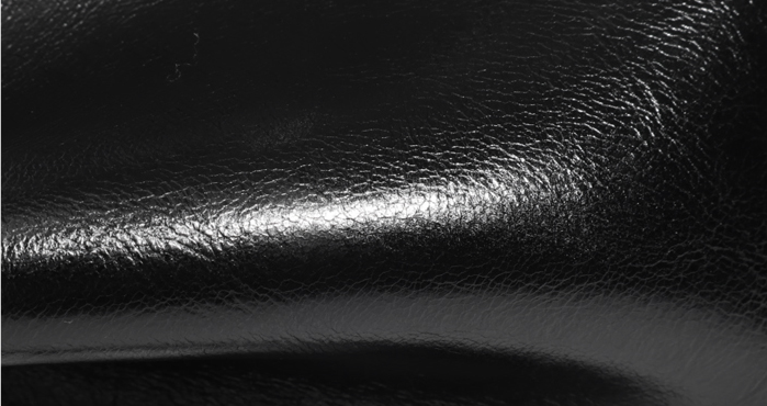 Gros plan de la texture et des reflets du cuir noir du sac Fanny