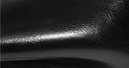 Gros plan de la texture et des reflets du cuir noir du sac Fanny