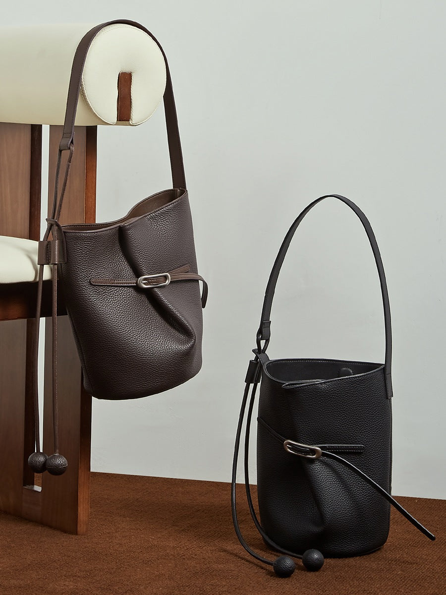 Sacs Isabella marron café et noir présentés sur une chaise et au sol