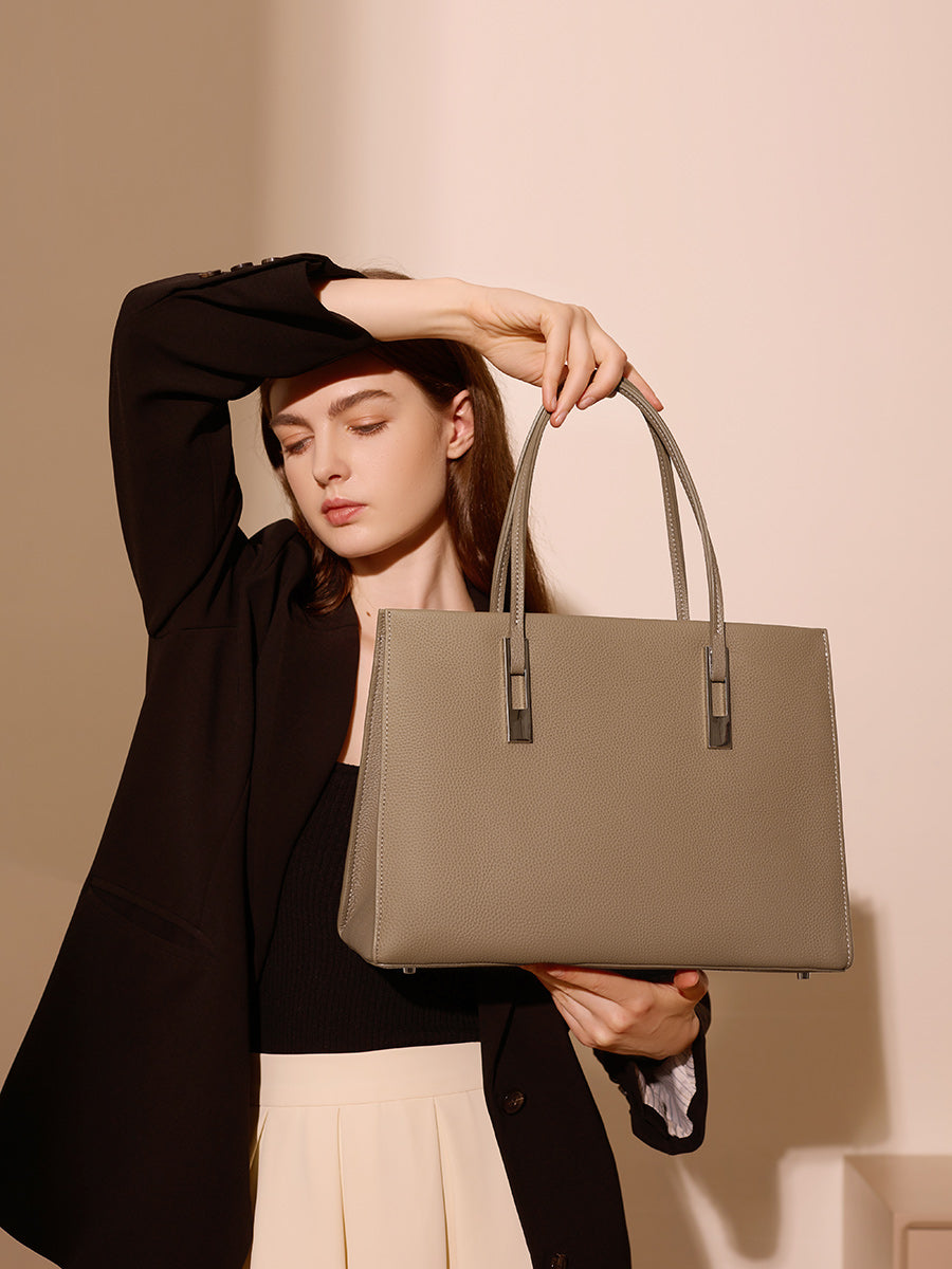 Sac Melinda taupe tenu par les anses par un modèle en blazer noir