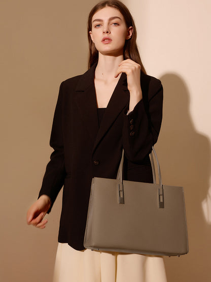 Sac Melinda taupe porté à l’épaule de face avec un blazer noir