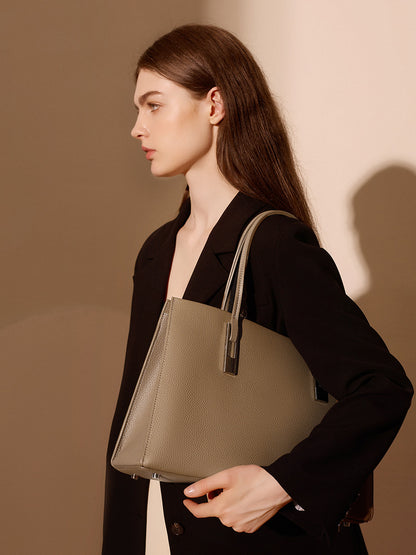 Sac Melinda taupe porté à l’épaule de profil avec un blazer noir