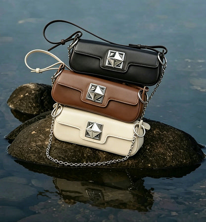 Sacs Monica noir, caramel et crème présentés sur des pierres au bord de l’eau