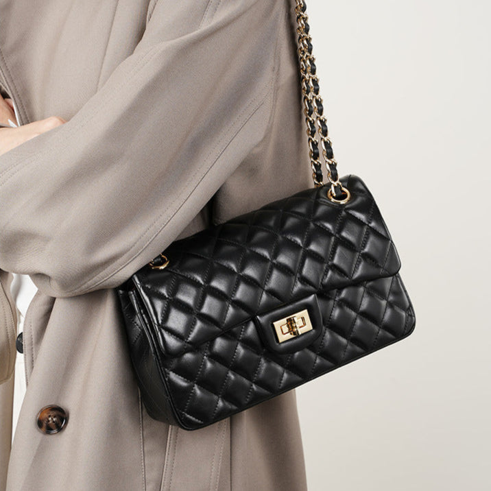 Femme portant le sac Zéphyr matelassé en cuir noir en bandoulière chaîne dorée