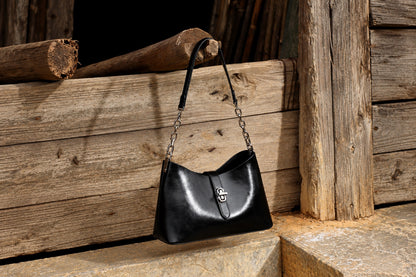 Sac Fanny noir avec sa bandoulière courte, présenté sur un banc en bois, vue large
