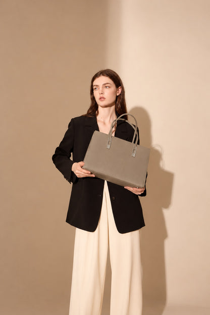 Sac Melinda taupe tenu devant soi par un modèle en blazer noir