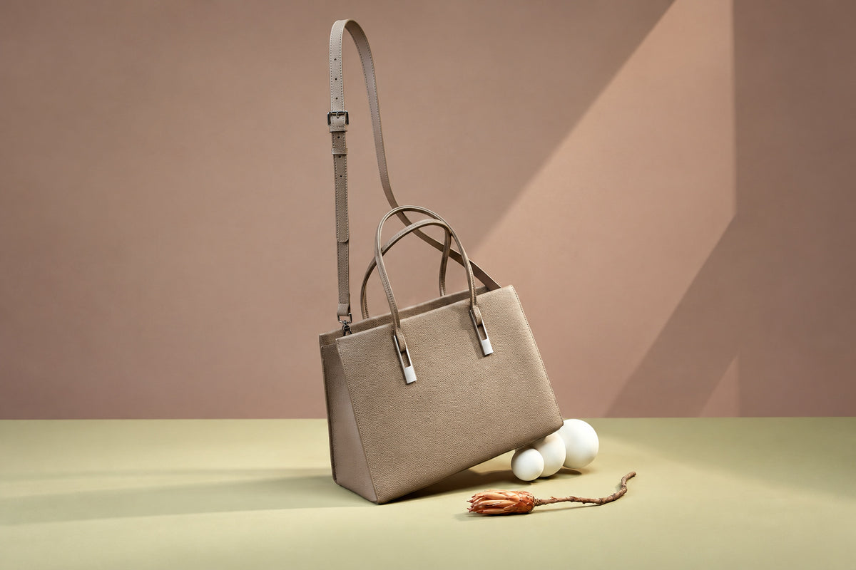 Sac Melinda taupe avec sa bandoulière dans un décor de studio élargi