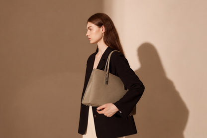 Sac Melinda taupe porté à l’épaule de profil dans un décor beige élargi