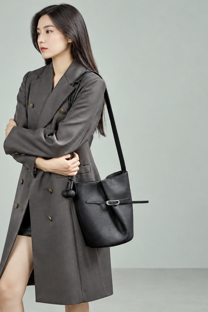 Sac Isabella noir porté à l’épaule avec un manteau gris