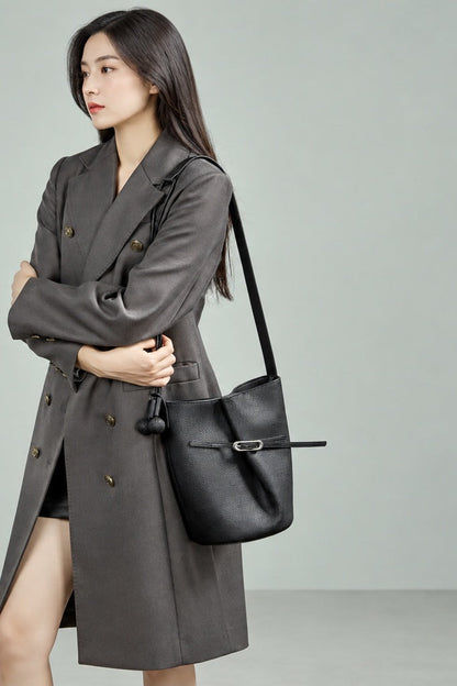 Sac Isabella noir porté à l’épaule avec un manteau gris
