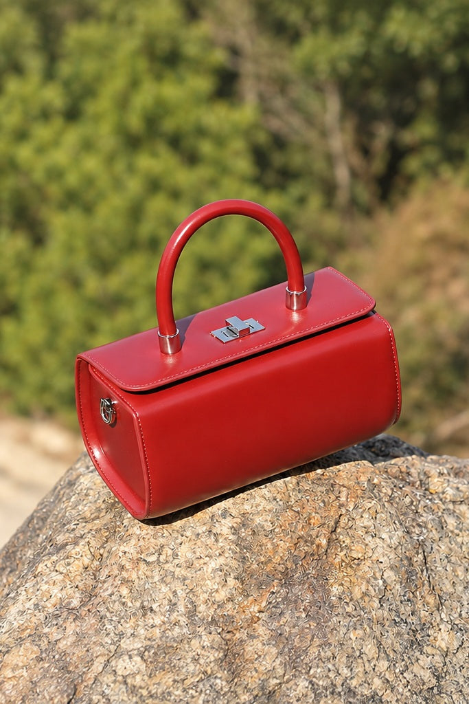 Sac Selena rouge en cuir, posé sur un rocher dans un décor végétal