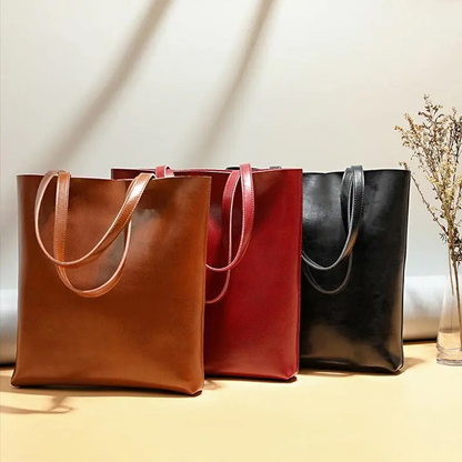 sac_fourre_tout_Luanda-en-cuir-trois modeles camel rouge et noir disposés l'un devant l'autre couvrant la moitié du sac de derrière , sur un meuble avec de la décration